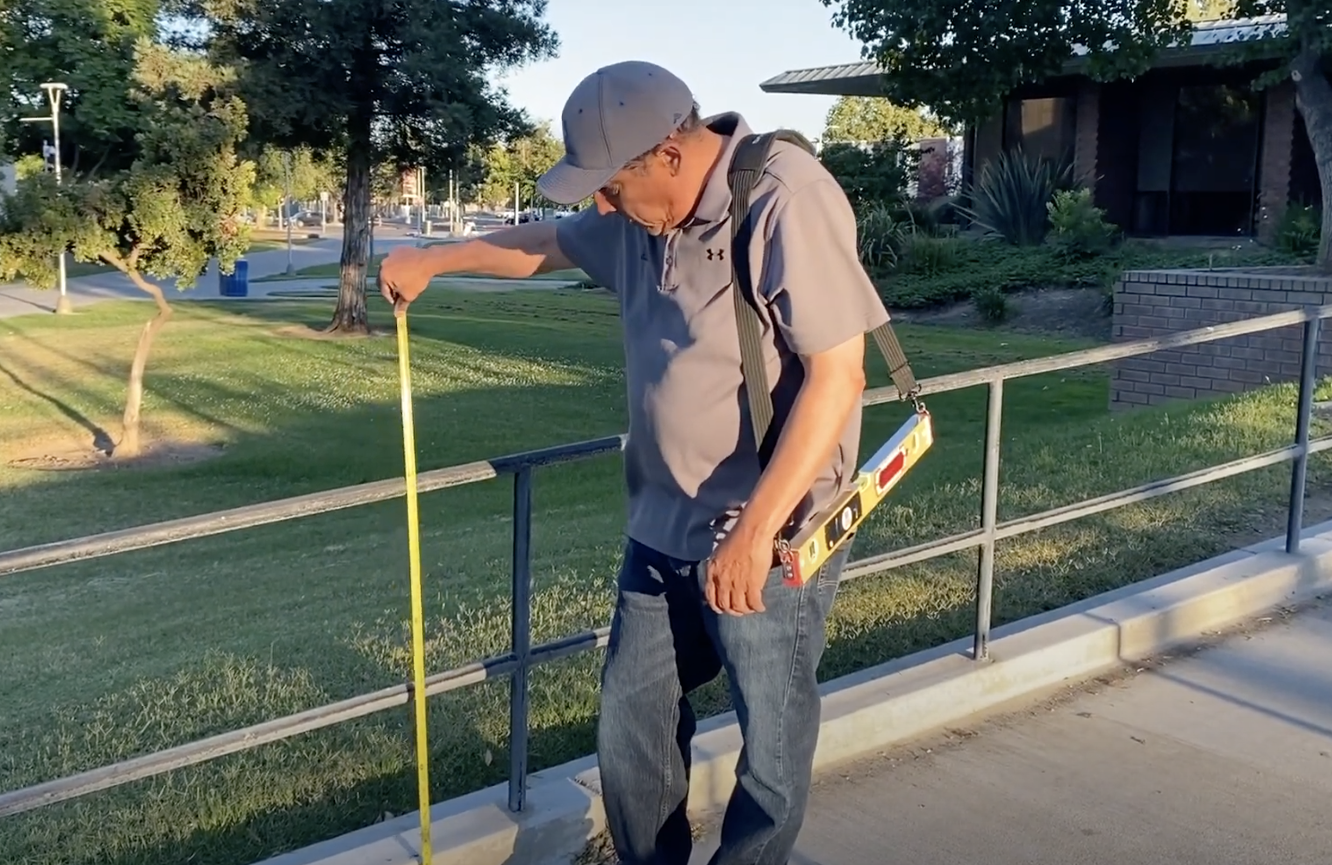 CASp inspector measuring a ramp handrail with a tape during an ADA compliance checklist walk-through